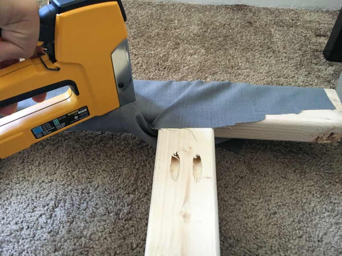 Stapling the fabric around the legs to hide the raw wood.