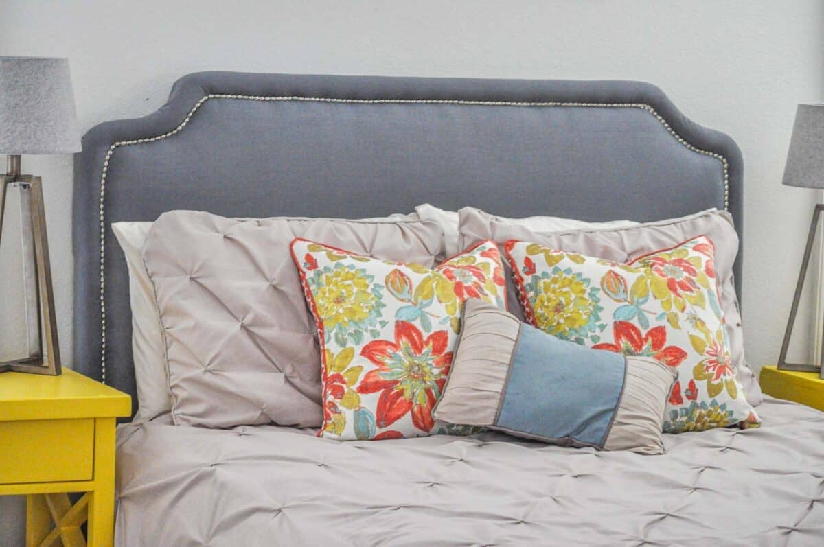The completed DIY headboard with nailhead trim with colorful pillows on the bed.