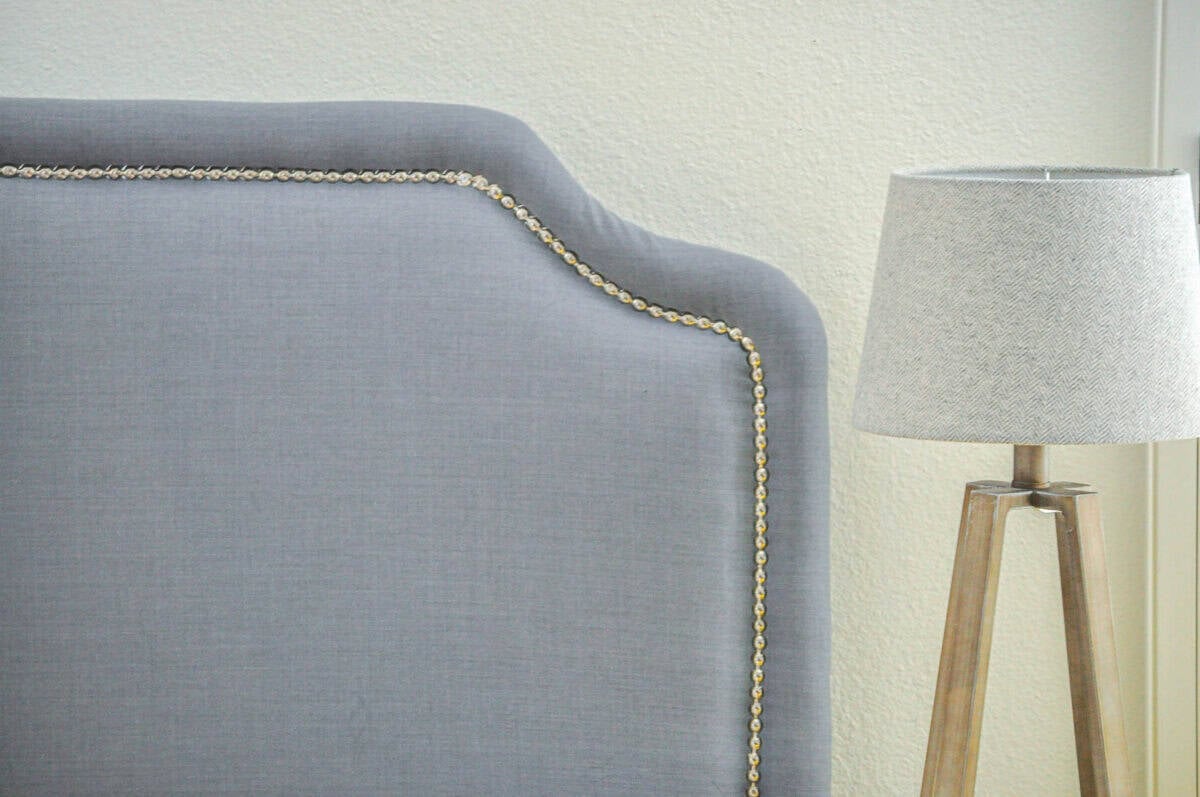 close up of the nailhead trim on a gray upholstered headboard