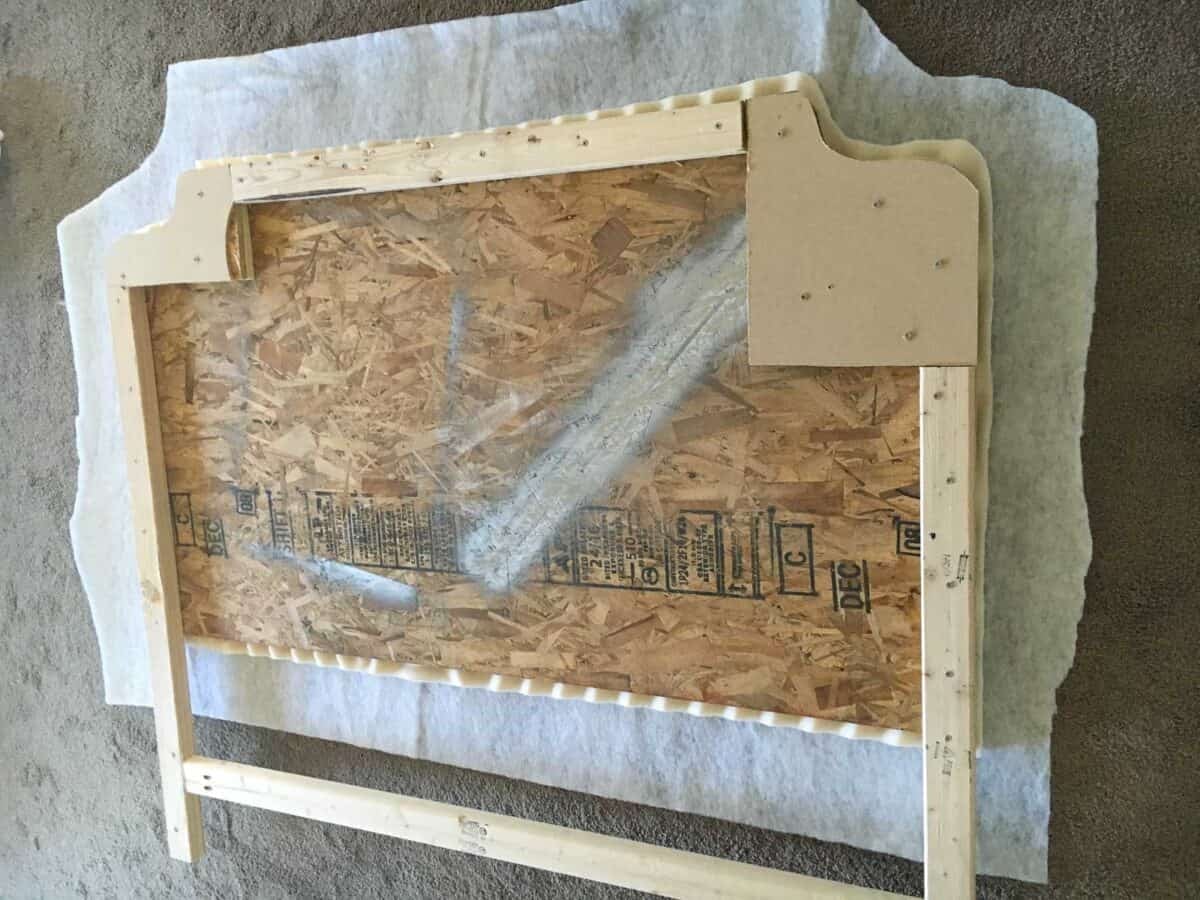 headboard laid out on top of the batting on a carpeted floor.