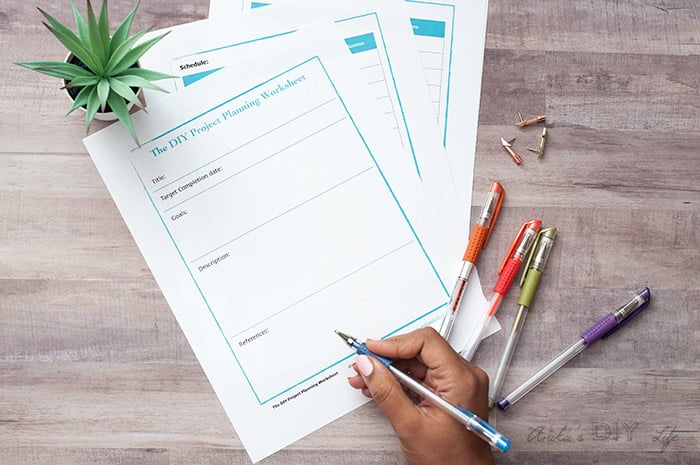 DIY project palnner worksheet with pens on wood surface