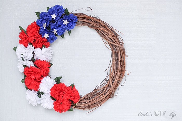 red white and blue wreath on the front door. How to make a red white and blue wreath using dollar store flowers.