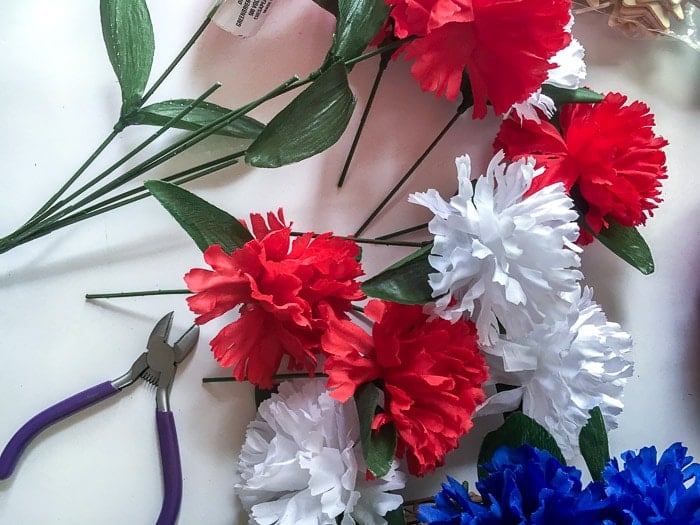 Cutting the stems off of the dollar store flowers to make a red white and blue patriotic wreath