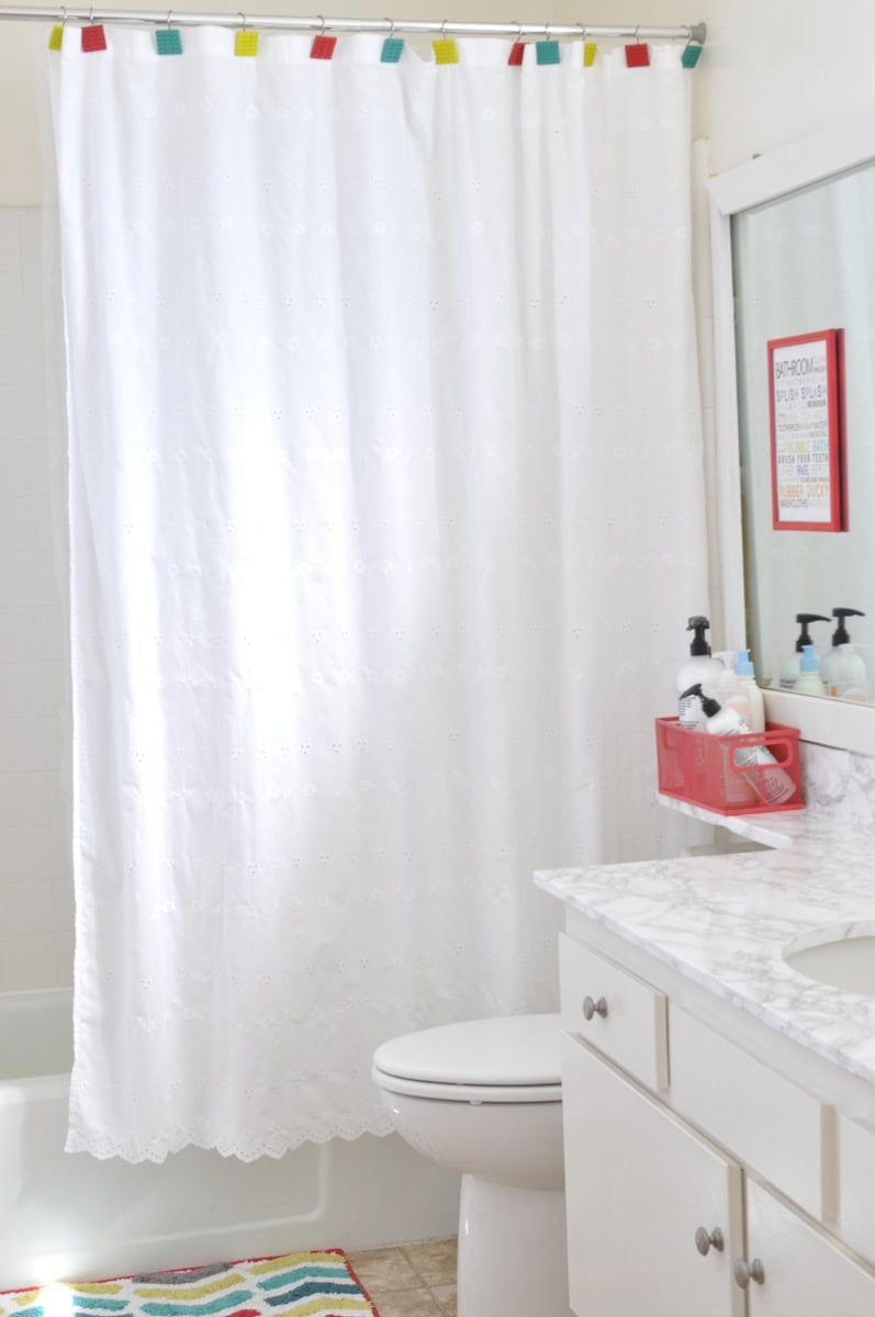 diy rental bathroom after with white marble countertop and colorful finishes.