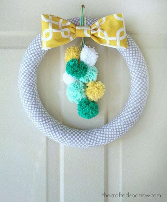 foam wreath wrapped in fabric with colorful pom poms