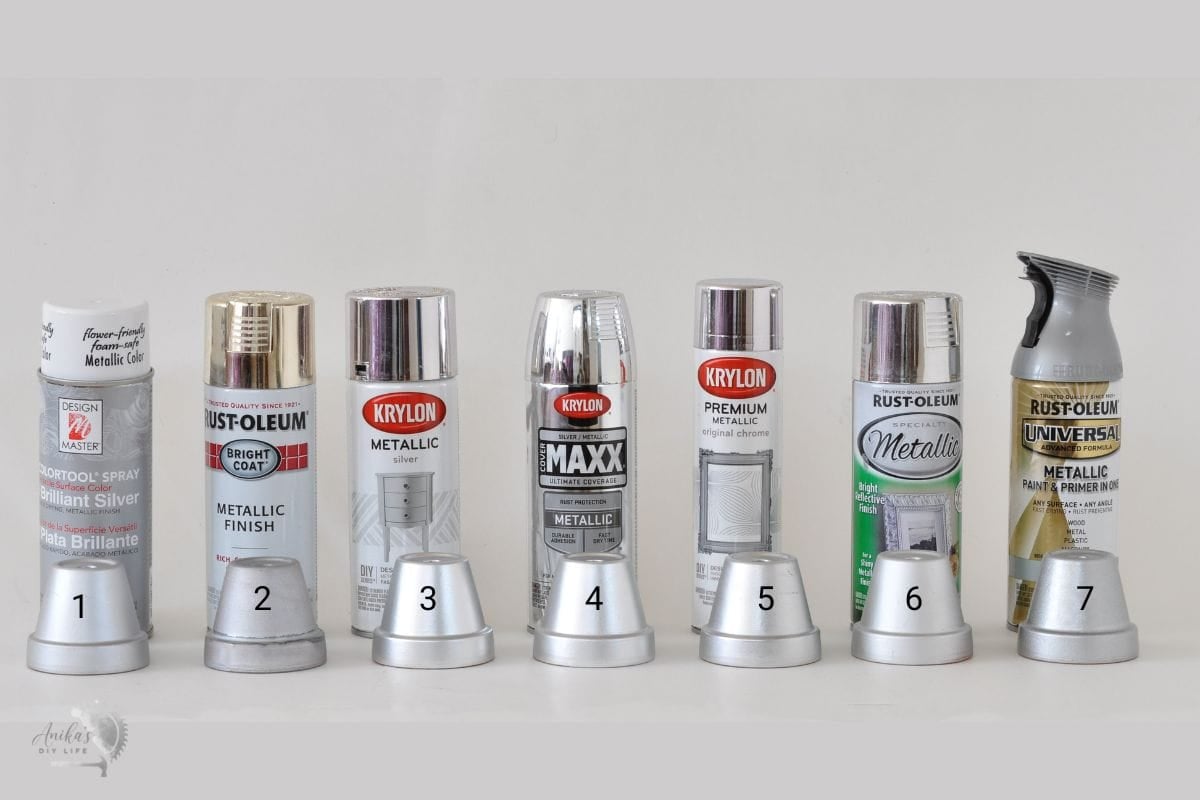 7 cans of silver spray paint with small plant pots sprayed with silver spray paint