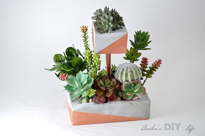Tiered concrete planter with faux succulents in it