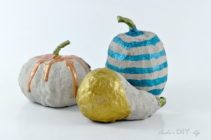 three DIY concrete pumpkins on a white background