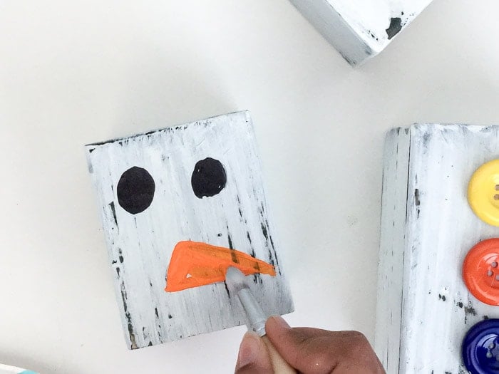 Painting orange nose on DIY wood block snowman