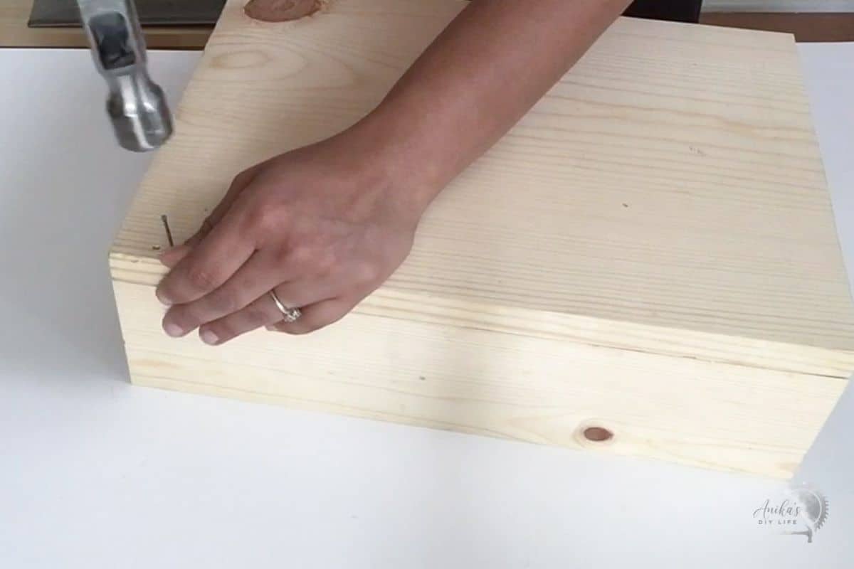 using hammer and nails to put the back on the DIY mail organizer