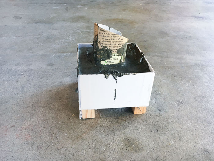 DIY concrete planter with wood feet poured and curing.