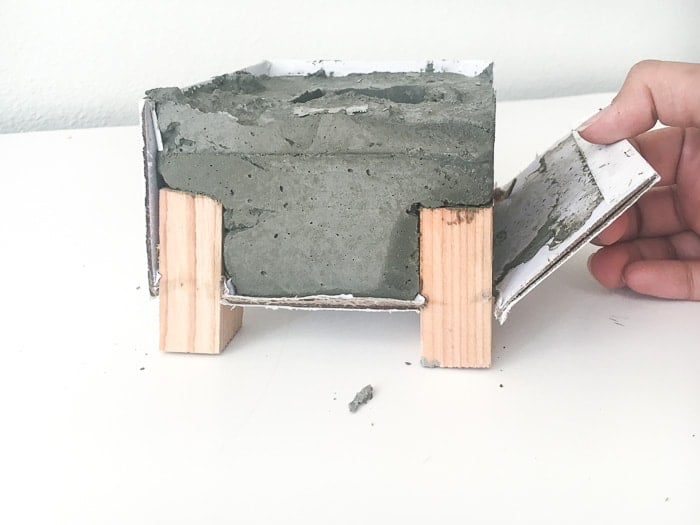 Removing cardboard from the DIY concrete planter with wood feet