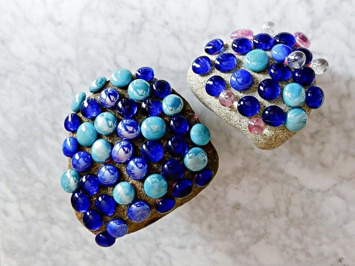 Making mosaic rocks by glueing gems to the rocks.