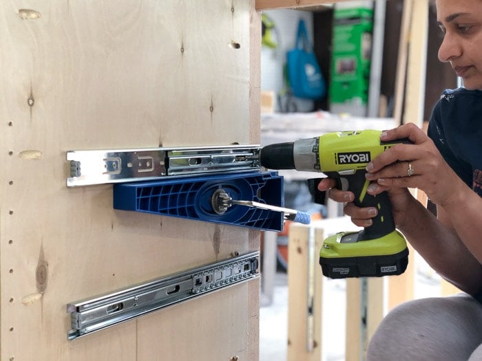 Installing drawer slides to the cabinet frame.