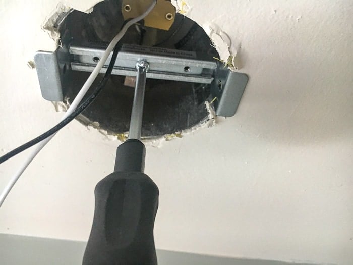 Tightening the crossbar to replace a recessed light with a pendant