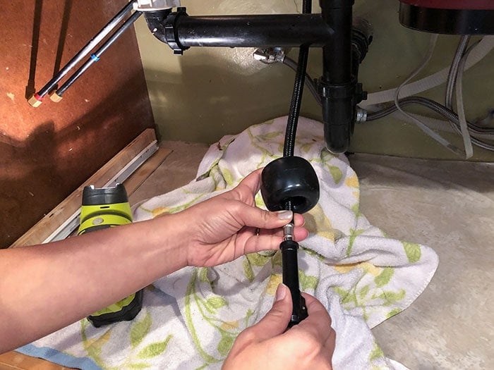 attaching the weight to the sprayer head under the sink and connecting to the water line