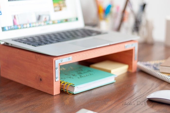 Coral laptop stand with laptop on top on a desk