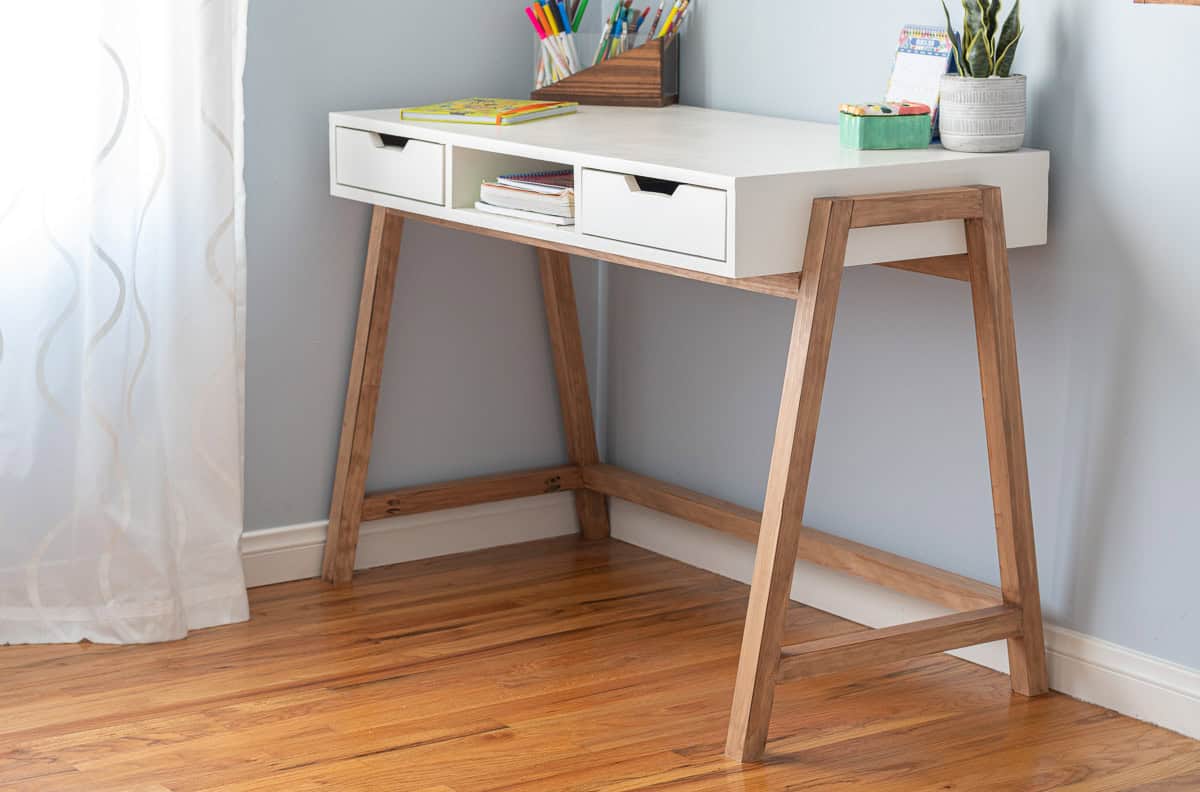 White plywood desk with drawerrs and A-frame legs in a room with wood floors