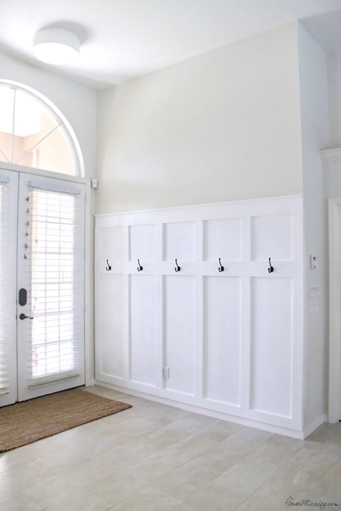 Entryway with white board and batten half wall and hooks