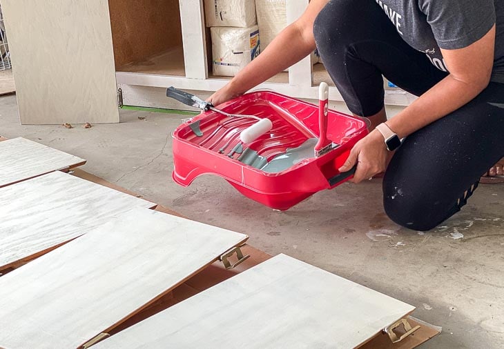 woman holding paint tray with paint for veneer cabinets