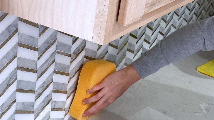 wiping down grout using a damp sponge
