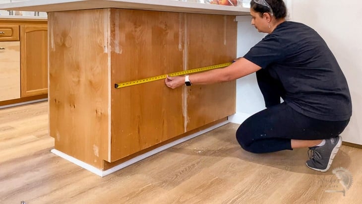 Woman measuring the kitchen island to calculate trim