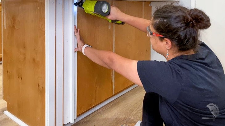 Woman attaching slats to a kitchen island with a brad nailer 