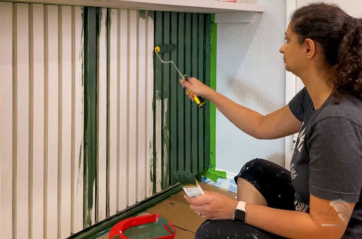 Woman painting the slat kitchen island with green paint