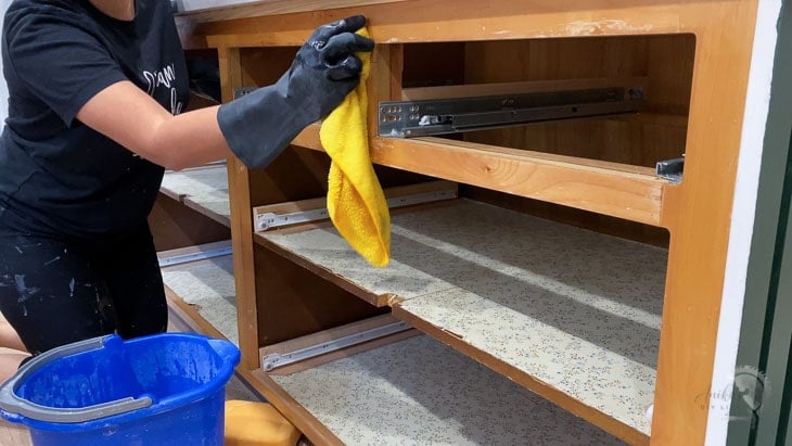 Woman cleaning cabinet with TSP to prepare for painting