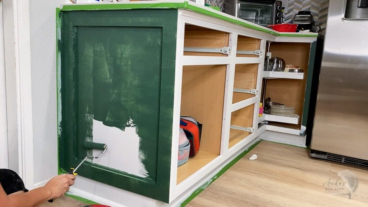 woman painting kitchen cabinets green