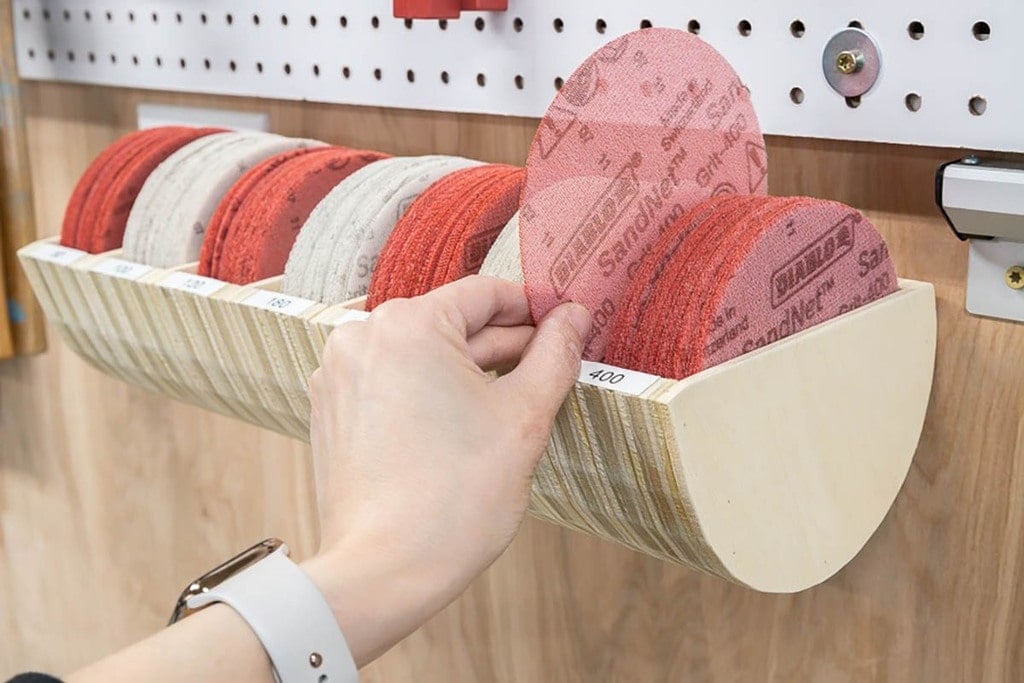 woman putting a sanding disk into a storage bin made from scrap plywood