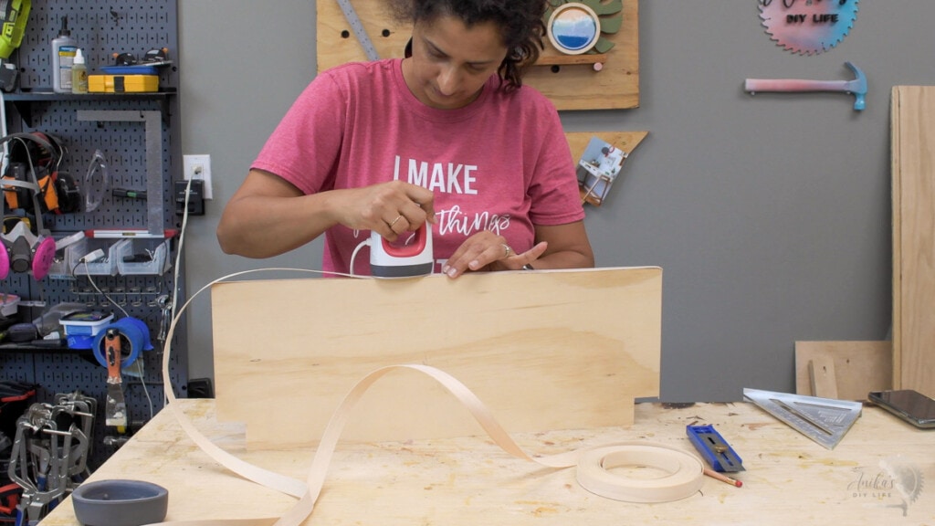 woman applying edge banding to a sheet of plywood