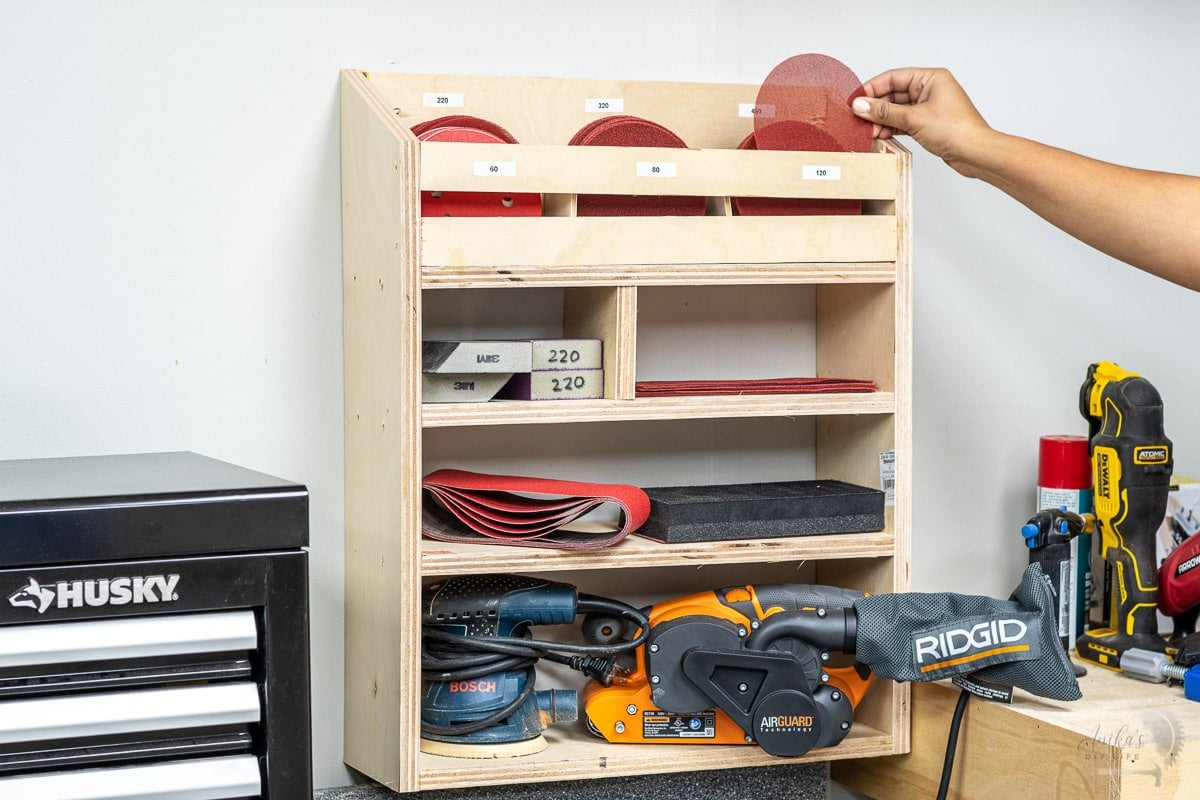 Woman picking up sandpaper from an organizer from a DIY sandpaper organizer