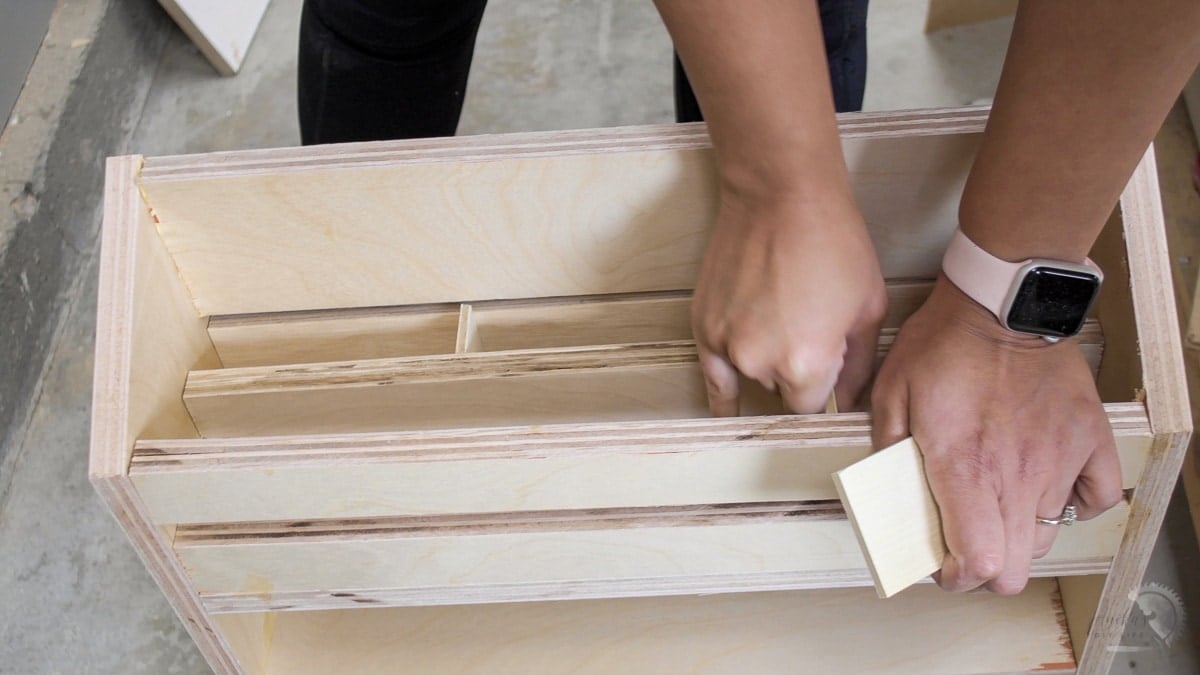woman adding dividers in the sandpaper organizer