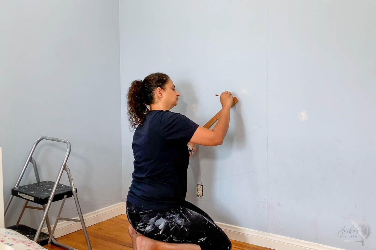 Woman drawing the sunburst pattern on the wall.