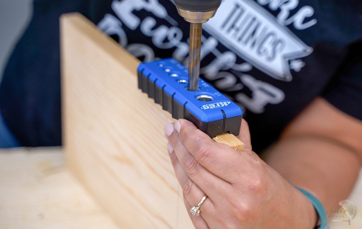 woman drilling hole into edge of board using kreg drilling guide