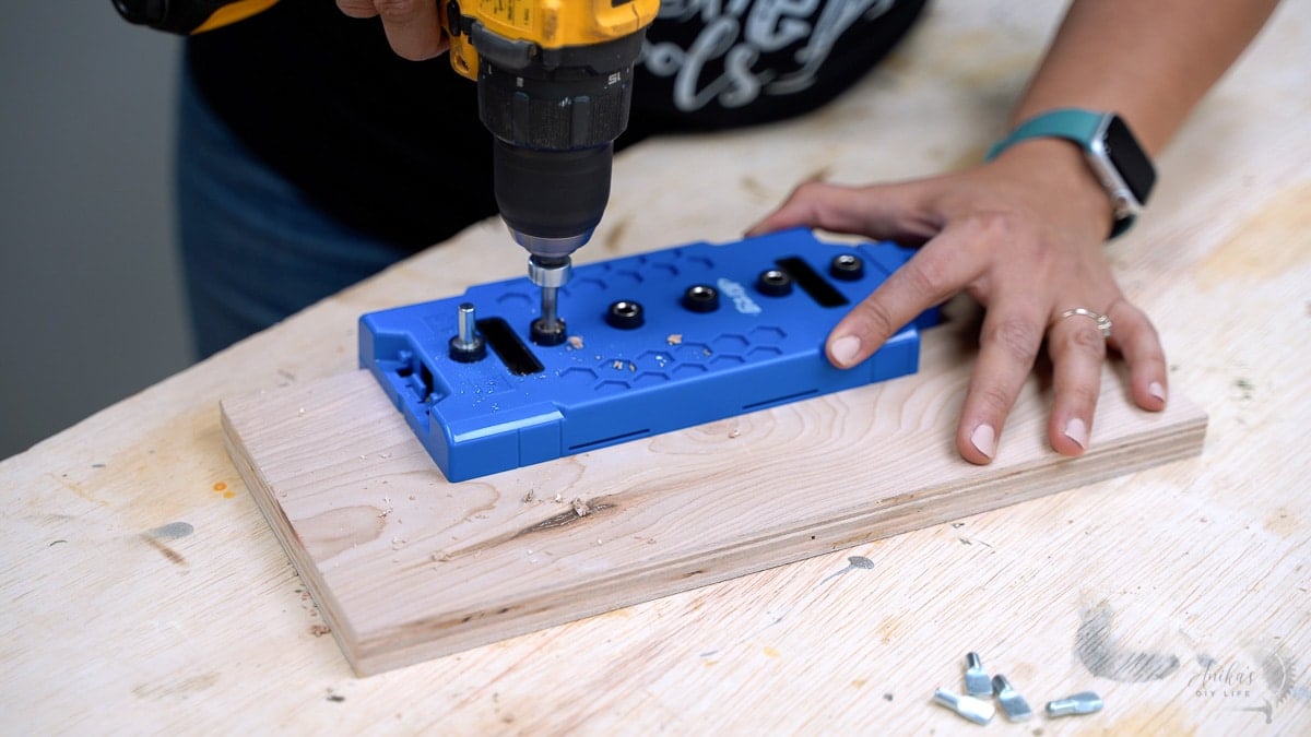 woman making shelf pin holes on scrap piece of plywood