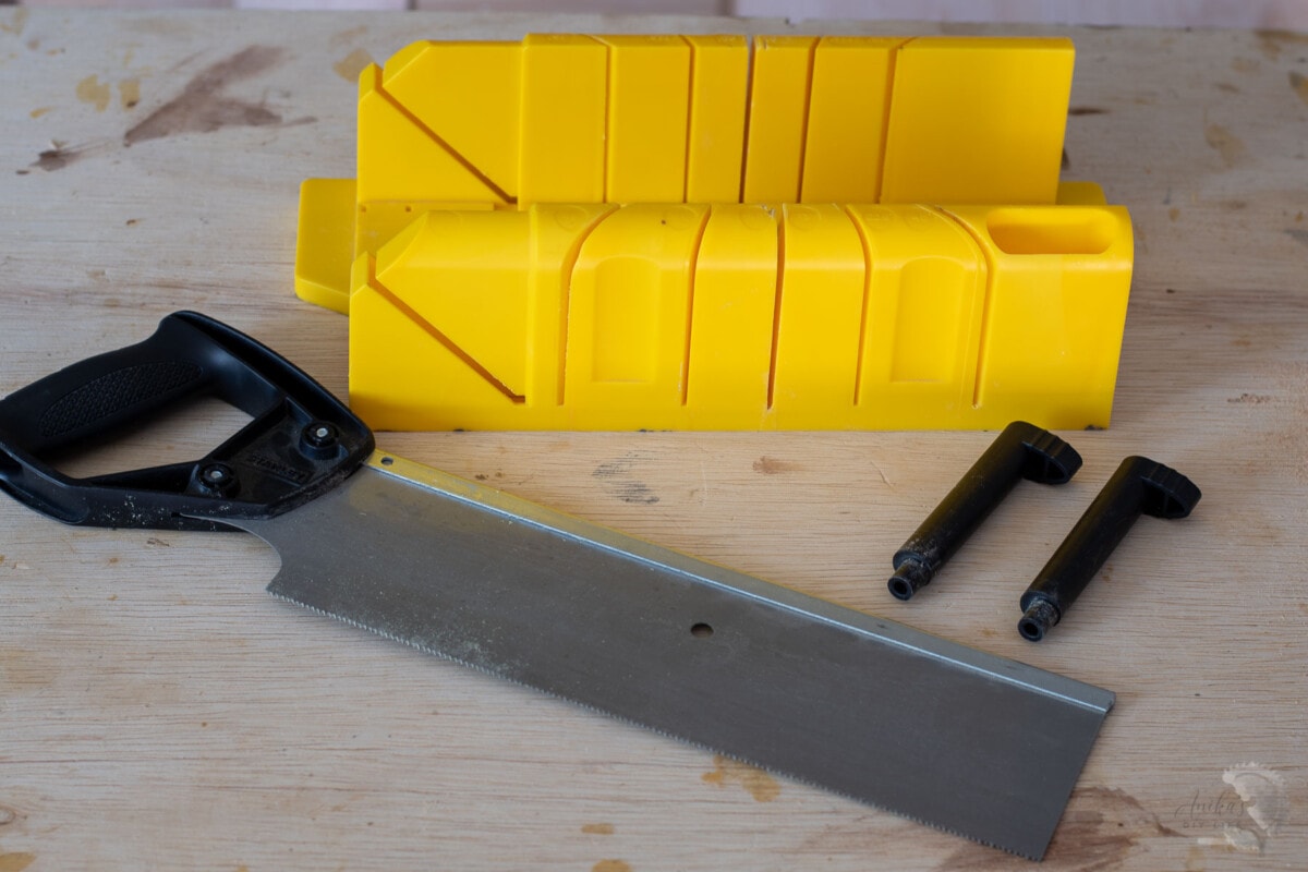 Miter box, hand saw and cam pins on a workbench.