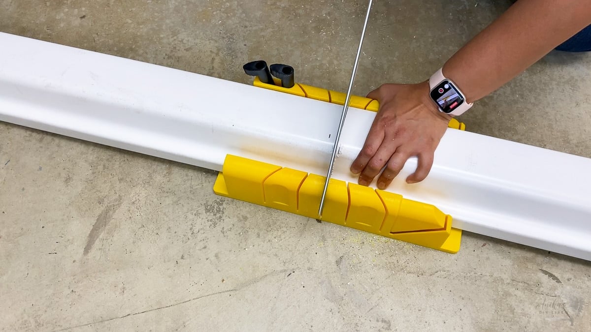 woman cutting rain gutters using miter box.