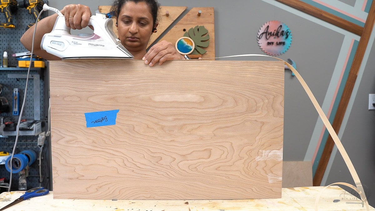 Woman applywin edge banding using an iron on a piece of plywood
