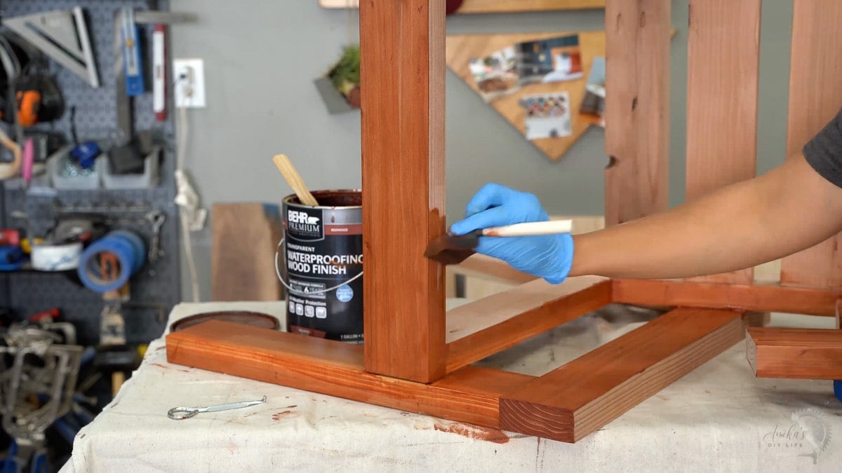 woman staining the outdoor chair