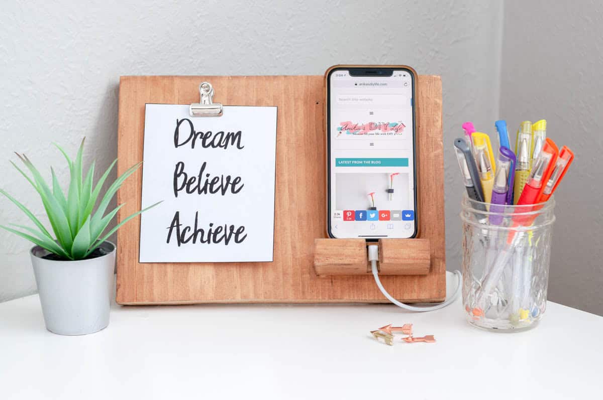 DIY phone holder with phone and handwritten note on desk