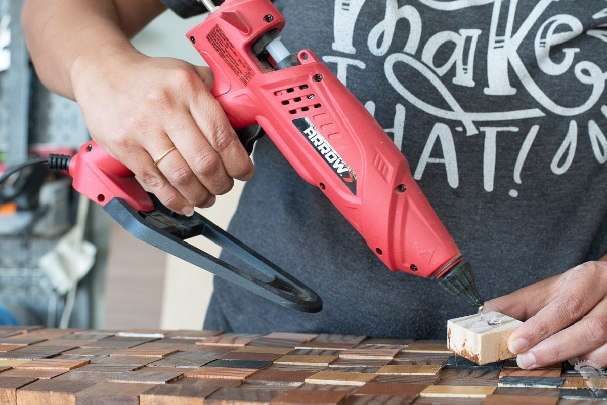DIY: Faça você mesmo esse lindo caminho de mesa usando restos de madeira 15 Mulher usando a pistola de cola Arrow para aplicar cola quente no bloco