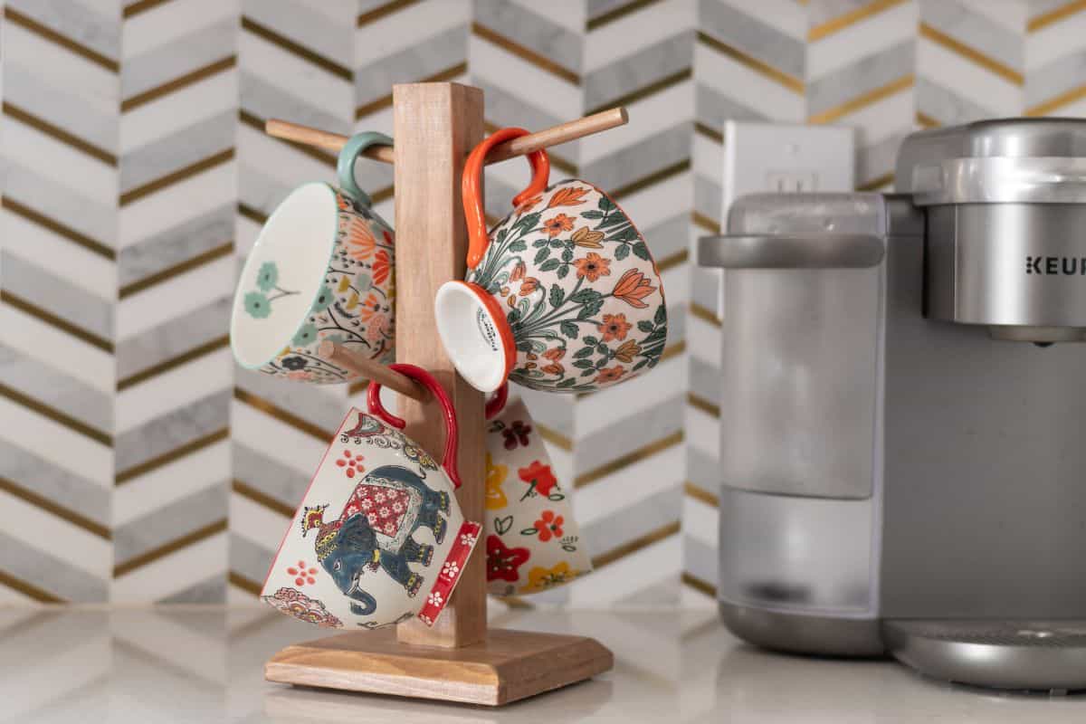 DIY mug tree with colorful patterned mugs hanging on it