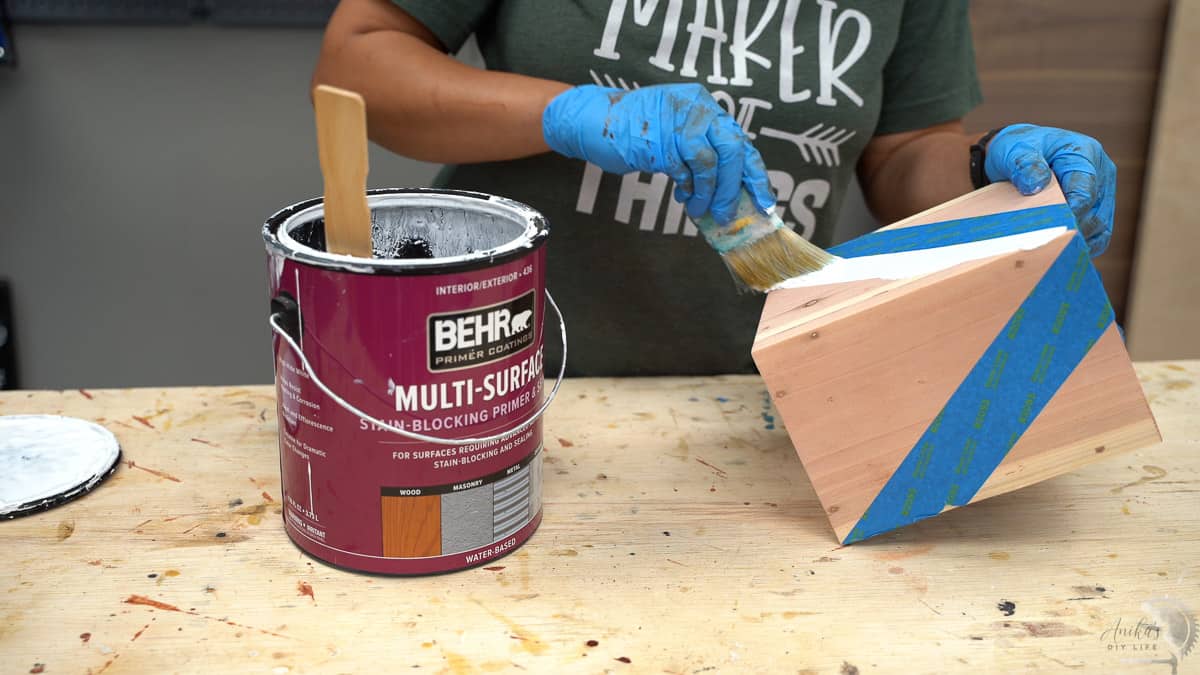 Vasos de Madeira DIY: Projeto Simples e Econômico para Iniciantes 17 mulher aplicando primer em um vaso de madeira
