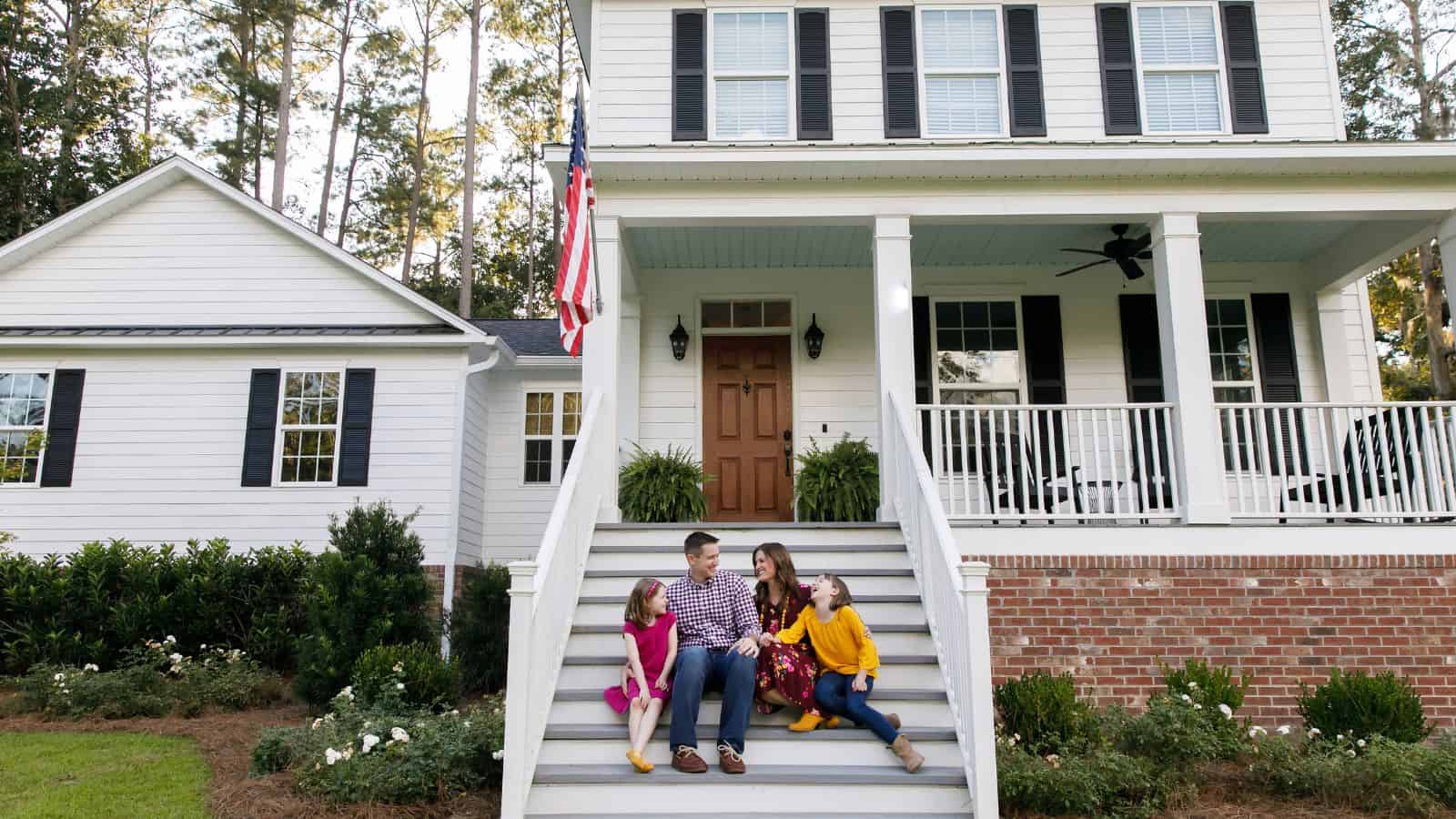 family sitting on front steps of their home