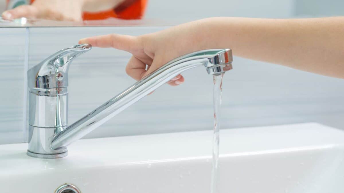 child turning off bathroom faucet