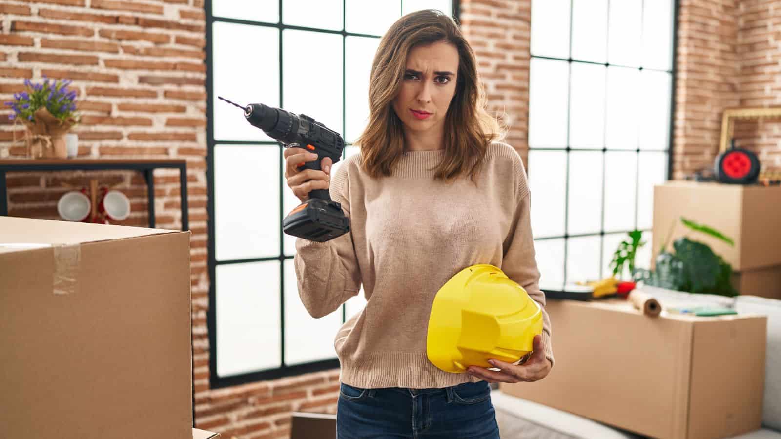Woman holding a drill and hard hat