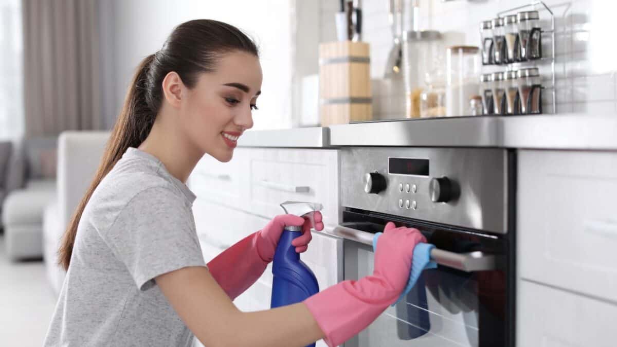 woman cleaning outside of stove