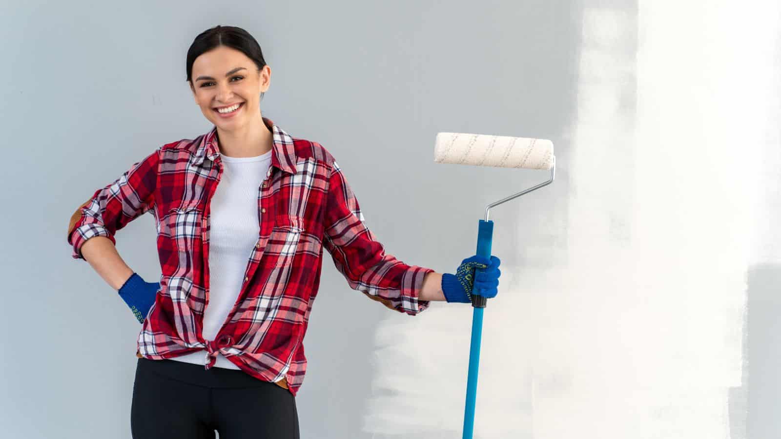 woman in front of partially painted wall with paint roller